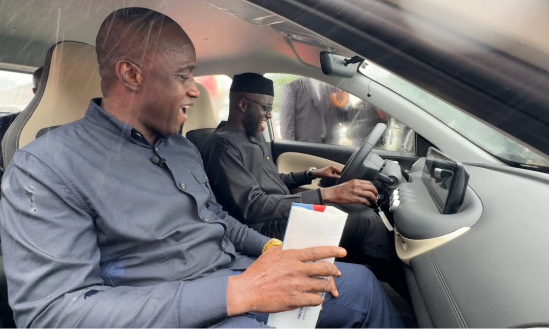 苏拉(左)与塞内加尔基础设施和陆空交通部长马利克·恩迪亚耶(右)体验新能源汽车。